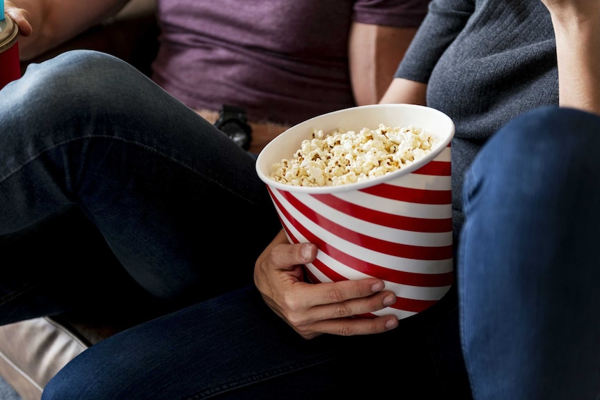 Two people eat popcorn.