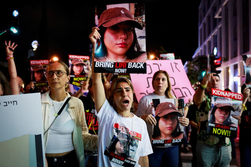 Protesters gather on a street holding signs and wearing t-shirts call for the immediate release of hostages