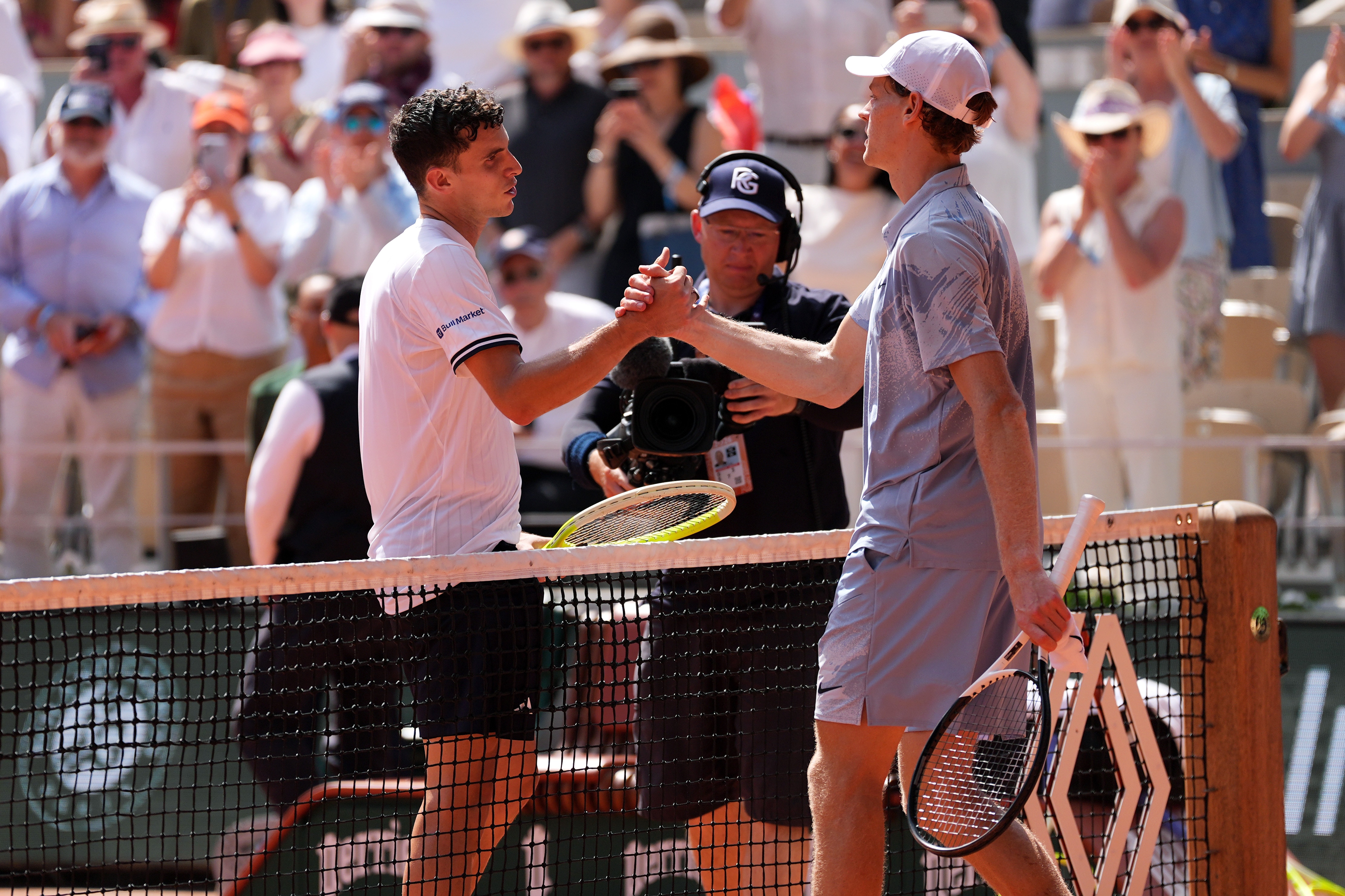 Juan Manuel Cerundolo shakes hands with Jannik Sinner at the net at French Open.