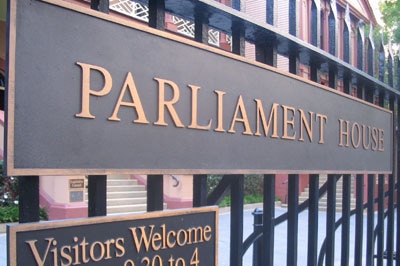 A metal gate with Parliament House written on it in brass
