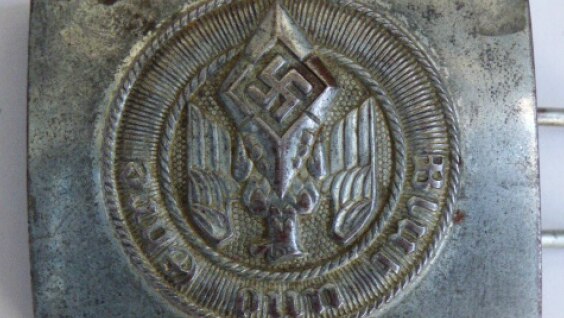 A silver belt buckle with a swastika on it, labelled as a Hitler Youth buckle