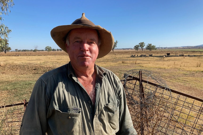 A middle aged man wearing an akubra standing in a field 