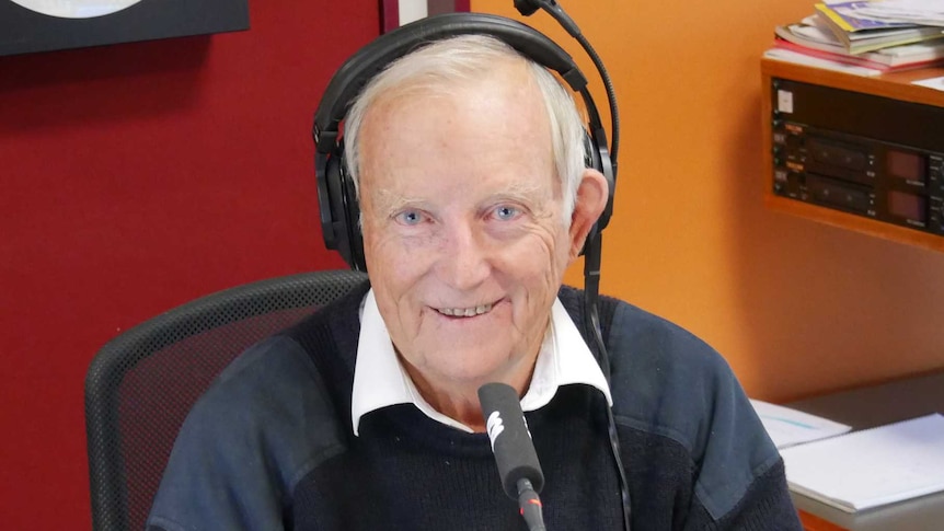 Pritchard, wearing headphones, sitting behind microphone in the studio.