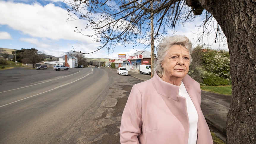 Ms Triffitt stands by the side of the empty Lyell Highway in Ouse. She is wearing a pink jacket.