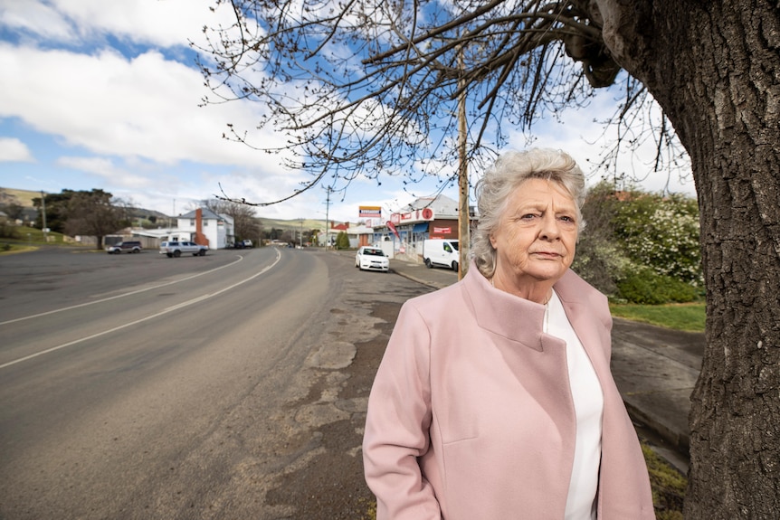 Ms Triffit stands by the side of the empty Lyell Highway in Ouse. She is wearing a pink jacket.