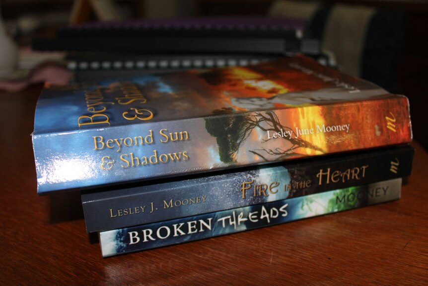 Three books stack on top of each other, sitting on a table.