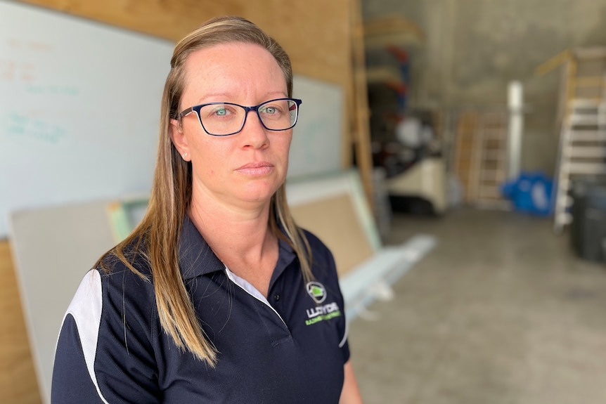 Woman wearing navy shirt and glasses standing in a warehouse.