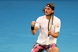 Stefanos Tsitsipas wearing a white shirt celebrates a winner on a tennis court