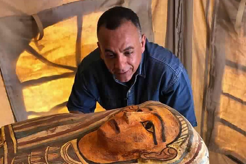 A man looking at an Egyptian coffin
