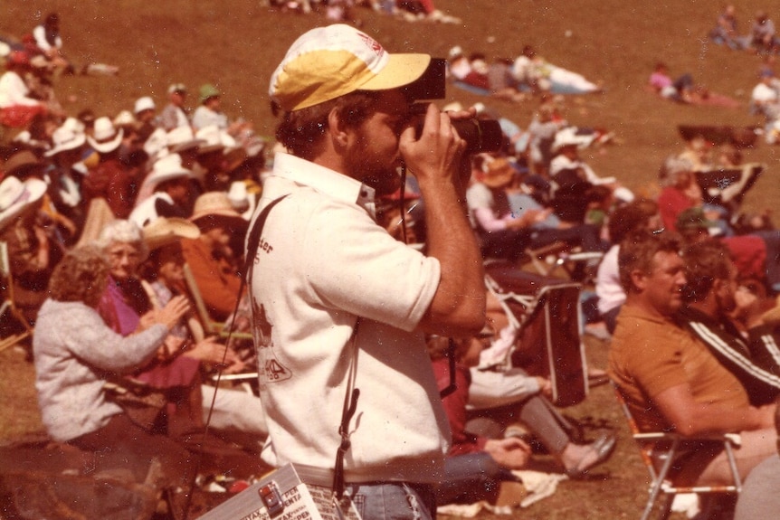 A man holds a camera as he takes a picture.