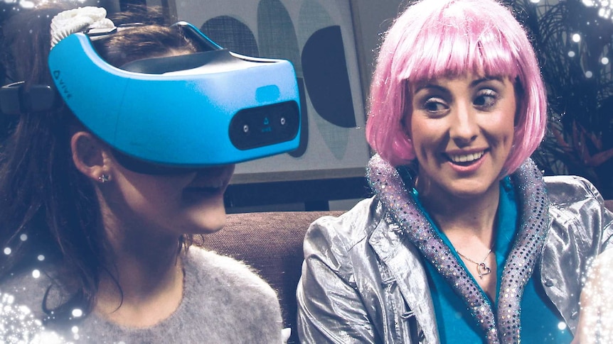 Emma dressed up in a 2060's spacey outfit sits on a couch next to a 2019 girl wearing a VR headset.