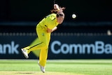 Australian seam bowler Megan Schutt stares down the pitch in her follow-through as the ball flies through the air in a T20I.