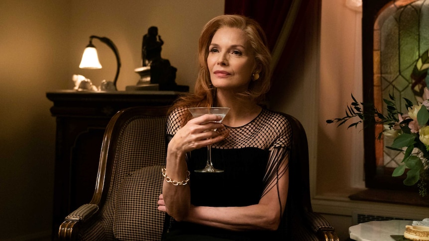 A scene from the film French Exit with Michelle Pfeiffer in fancy dress holding a glass of wine