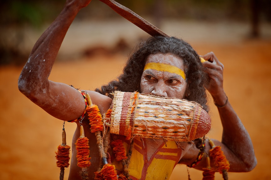 An Aboriginal dancer with a dilly bag around his neck and 