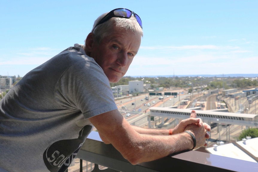 Ian, a homeless man who has taken part in a running program, leans on the edge of a balcony in East Perth.