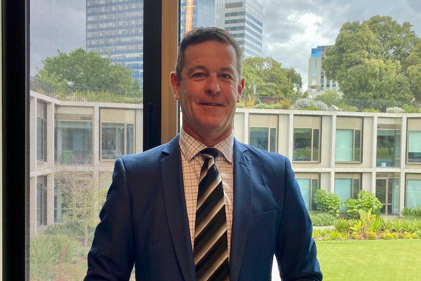 A man in a suit standing in front of a window inside Parliament House