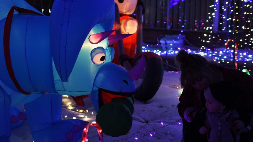 An inflatable dinosaur is surrounded by Christmas lights.