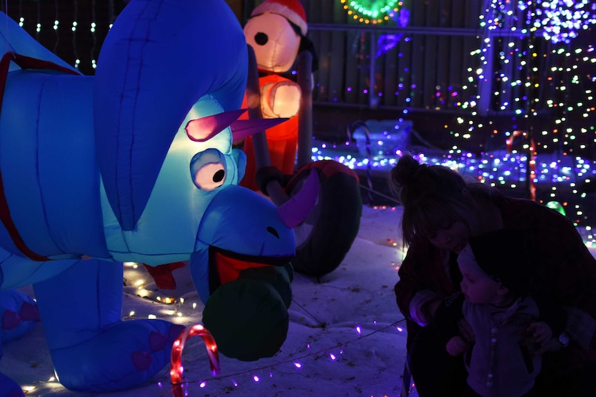 An inflatable dinosaur is surrounded by Christmas lights.