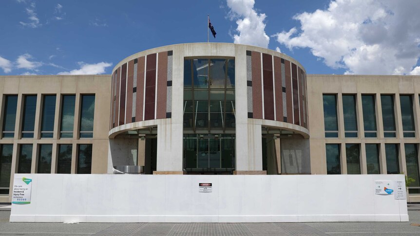 A construction fence surrounds the Senate entrance of the Parliament House building in Canberra. An Australian flag flies on top