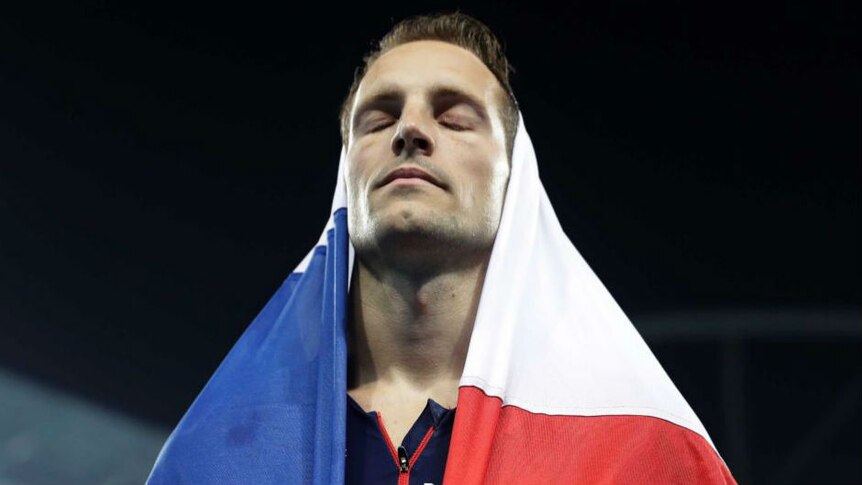 Renaud Lavillenie closes his eyes while standing on the podium with a French flag held on his head. Photo: AP