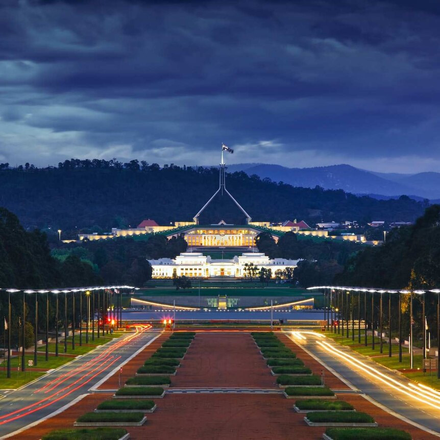 Looking down on Parliament House in Canberra at sunset, dark clouds behind the building