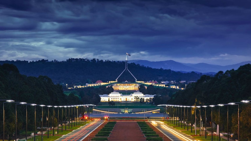 Looking down on Parliament House in Canberra at sunset, dark clouds behind the building