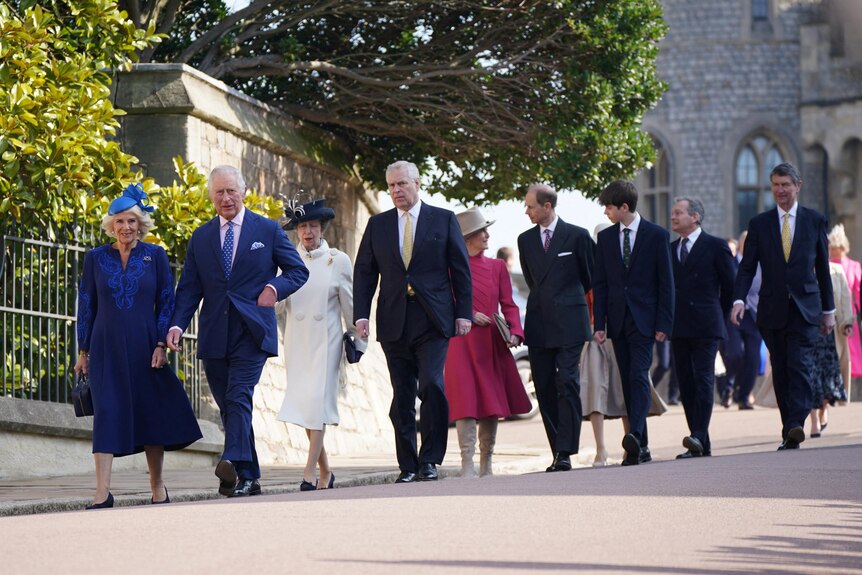King Charles III and the Queen Consort lead members of the royal family down a street
