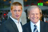 Actor Brad Pitt stands next to director Wolfgang Petersen smiling to camera. 
