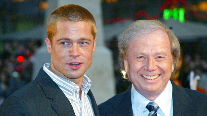 Actor Brad Pitt stands next to director Wolfgang Petersen smiling to camera. 