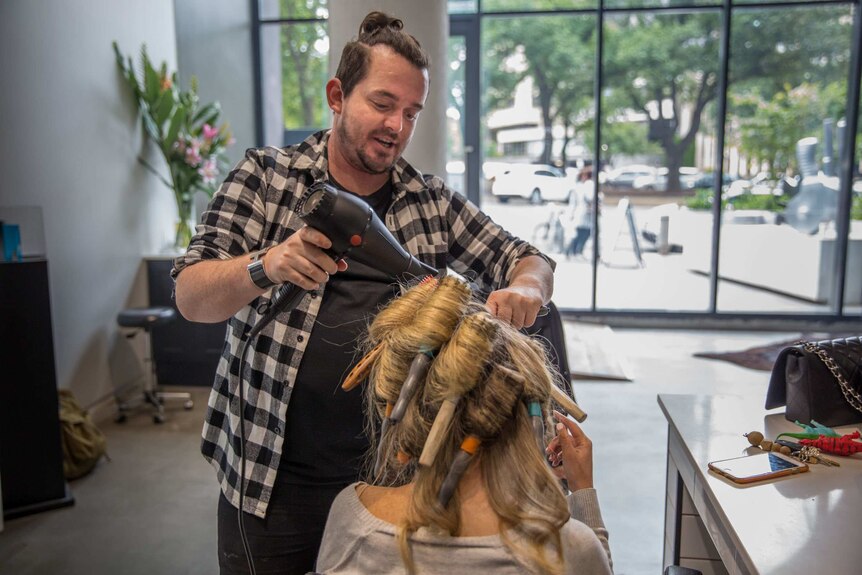 Christian Gillon drying a client's hair in a hair salon.