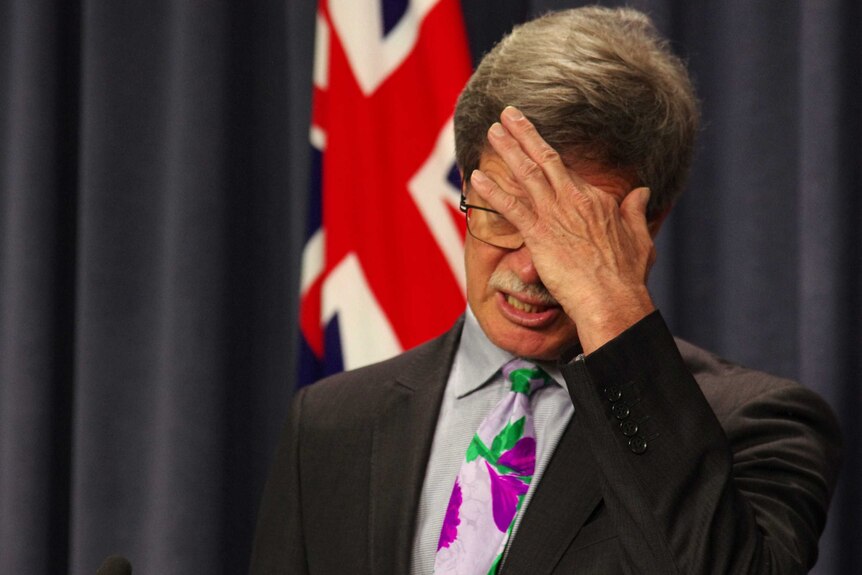WA Treasurer Mike Nahan scratches his furrowed brow while talking at a press conference.