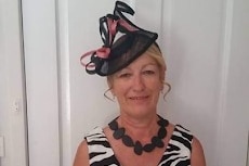 A woman dressed for the races smiles for a portrait.