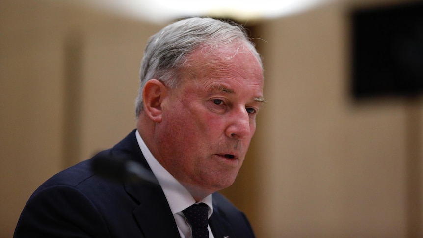 Richard Colbeck looks down while answering questions at a hearing inside parliament house