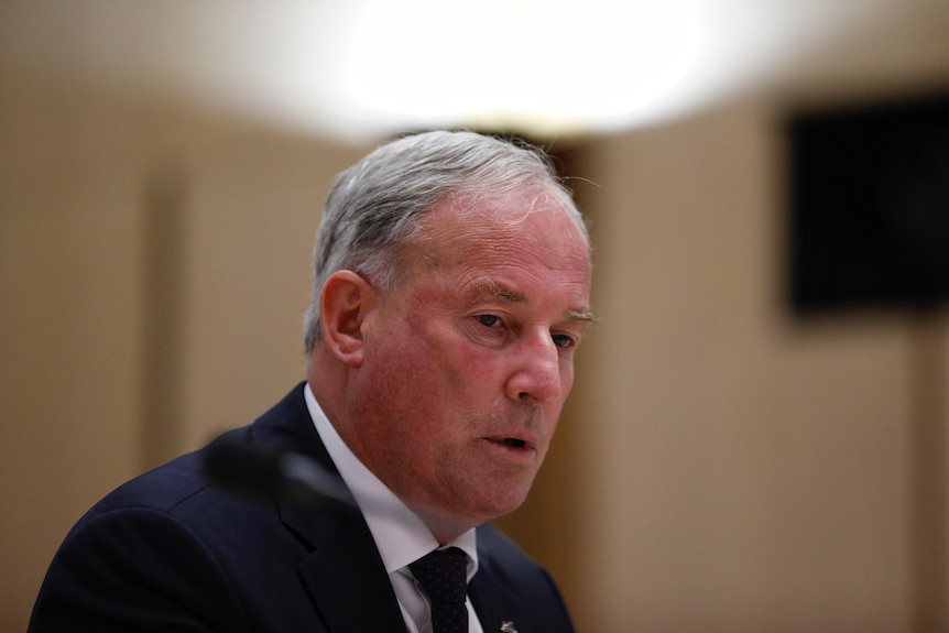 Richard Colbeck looks down while answering questions at a hearing inside parliament house