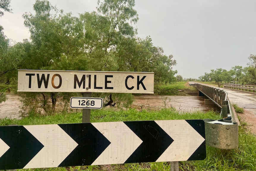 Shot of a sign of the Two Mile Creek crossing, there's heavy water in the creek.