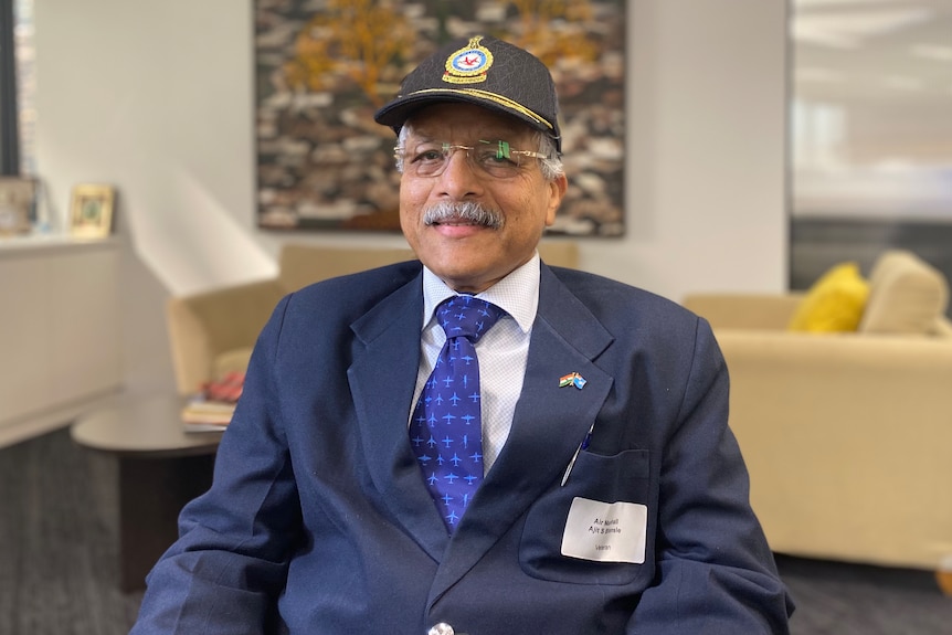 Ajit Bhonsle wearing an airforce cap, suit and tie. 