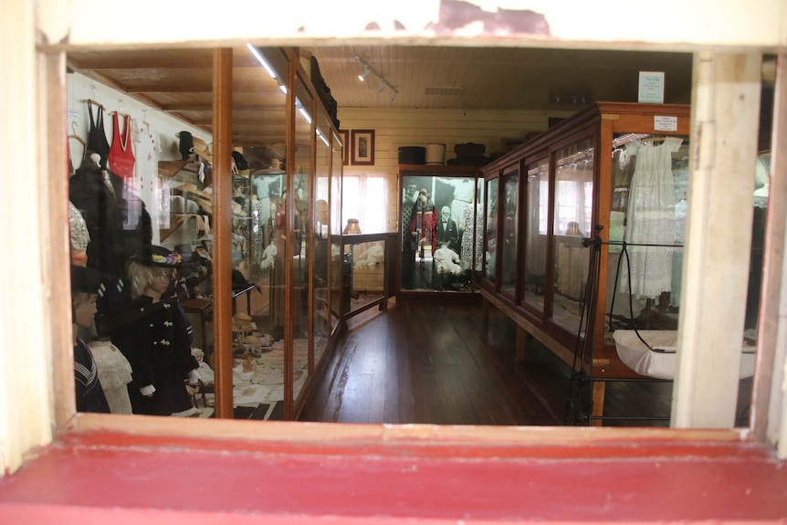 A museum type room with period clothes behind glass. 