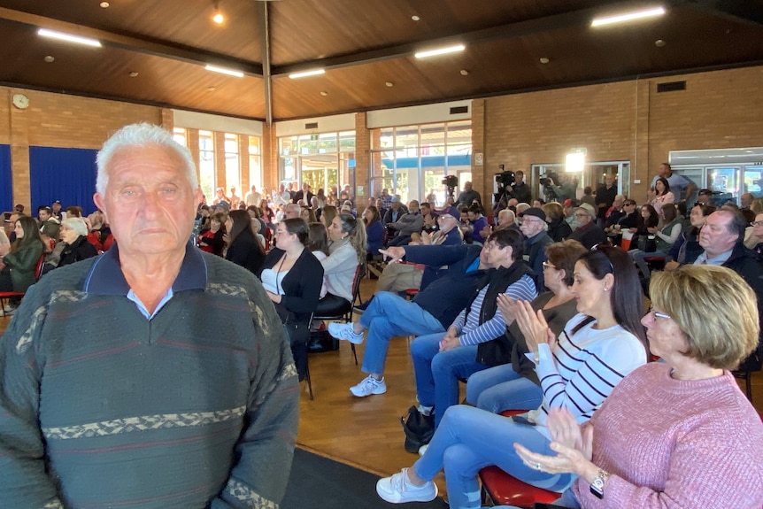 a man looking into the camera during a town hall meeting in the audience