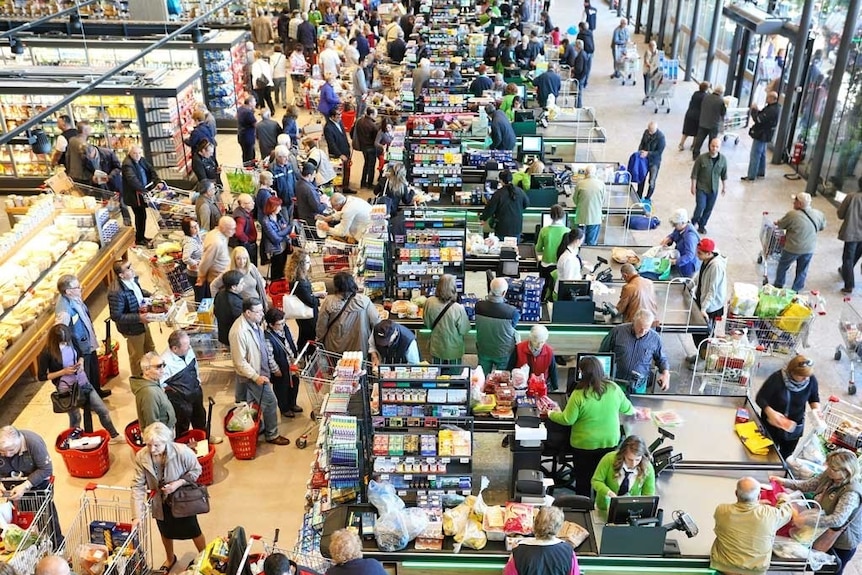 A packed supermarket with jammed checkouts, seen from above.