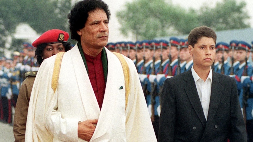 Moamar Gaddafi and his son Saif Ul-Islam inspect troops in 1989.