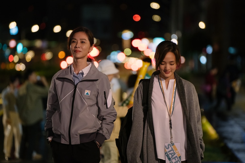 Two Taiwanese women walking with blurry lights in the background.