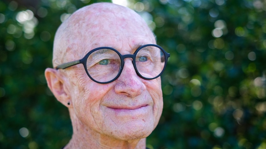 an older man wearing glasses smiling