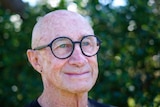 an older man wearing glasses smiling