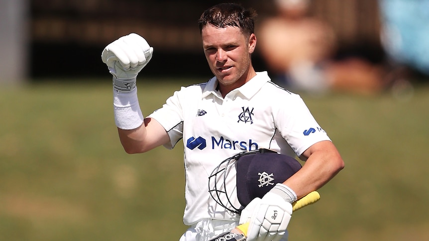 A Victorian male batter pumps his right fist after scoring a Sheffield Shield century.