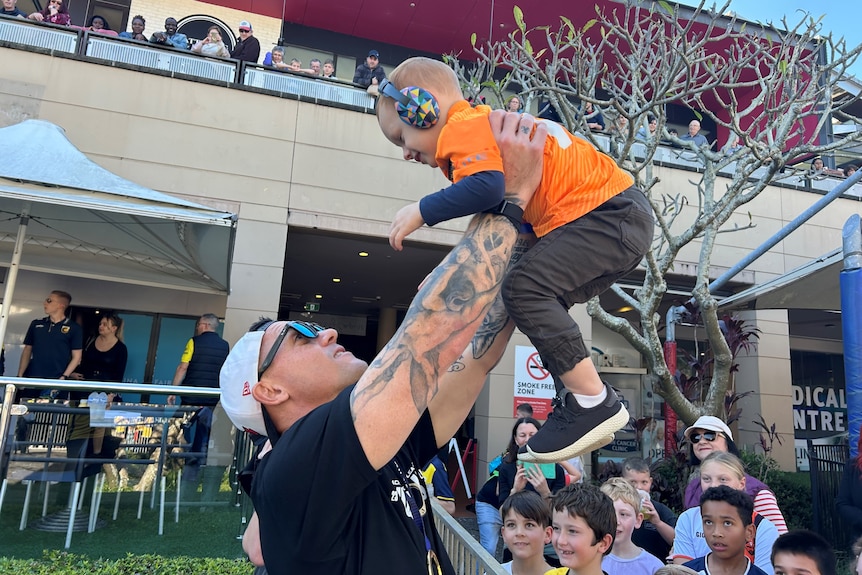 Central Coast Mariners captain Danny Vukovic throws a child in the air at celebartion following their a-league grand final win