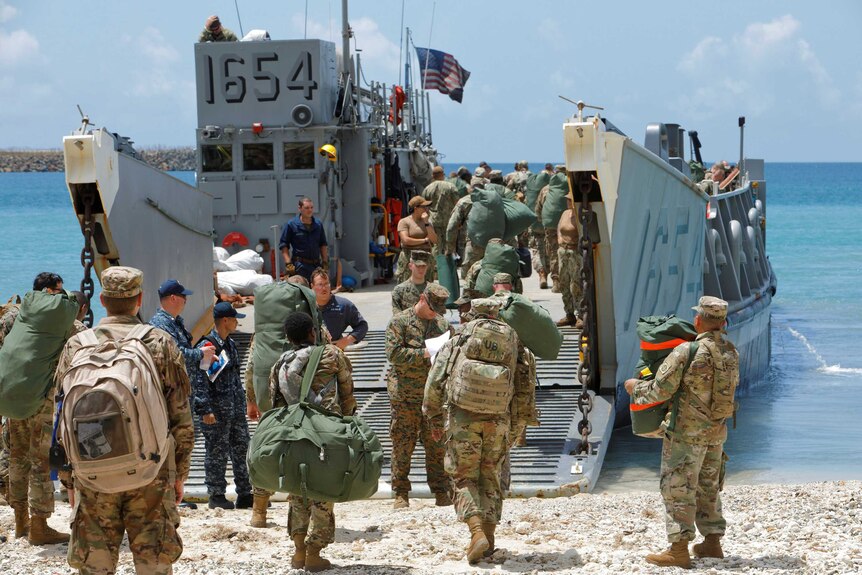 Soldiers board a navy landing craft.