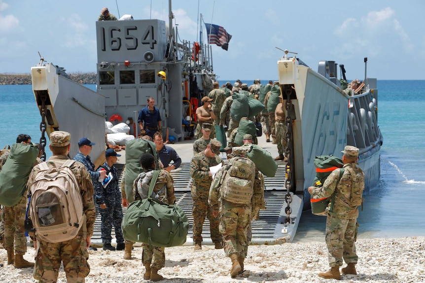 Soldiers board a navy landing craft.