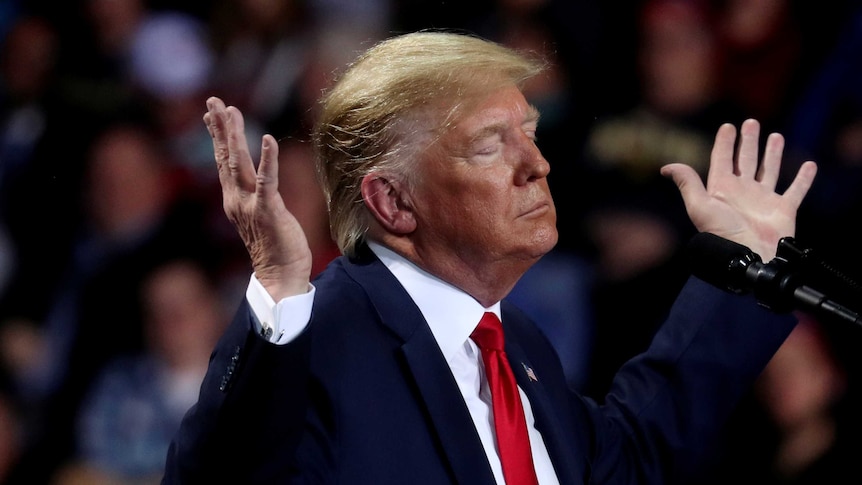 Donald Trump with his eyes closed and his hands thrown to the heavens