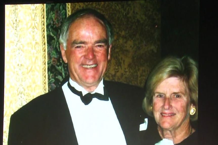 een foto van Neil Kerley en zijn vrouw in formele kleding weergegeven op het scherm met een kist ervoor, bedekt met een Sanfl-banner