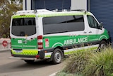 An ambulance parked outside a closed garage door.